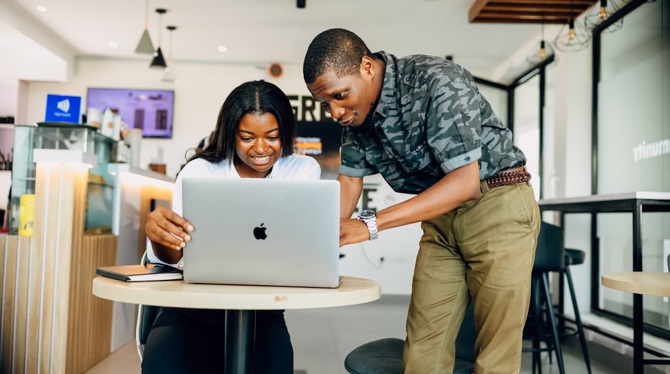 Two colleagues review a procedure on a laptop
