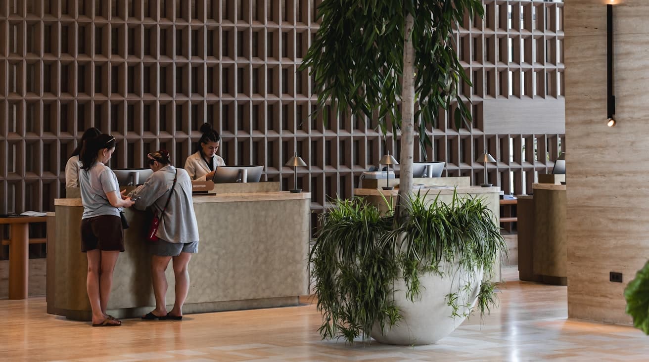 Réception d'un hôtel moderne : l'équipe au comptoir répond aux clients